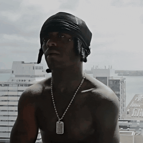 A Shirtless Man Wearing A Black Bandana And A Necklace With A Dog Tag On It GIF