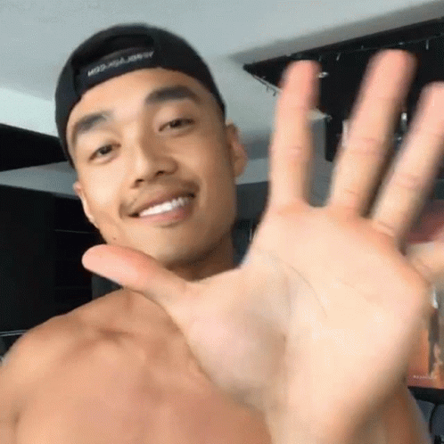 A Shirtless Man Wearing A Hat That Says Miss Usa On It Waves His Hand GIF