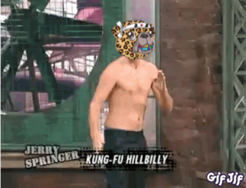A Shirtless Man Wearing A Leopard Mask Is Standing In Front Of A Building . GIF