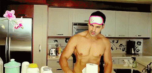 A Shirtless Man Wearing A Pink Eye Mask Is Standing In A Kitchen . GIF