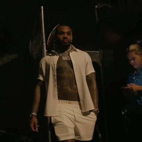 A Shirtless Man Wearing A White Shirt With A Greek Key Pattern On The Sleeves GIF