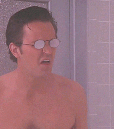 A Shirtless Man Wearing Glasses Is Taking A Shower In A Bathroom GIF