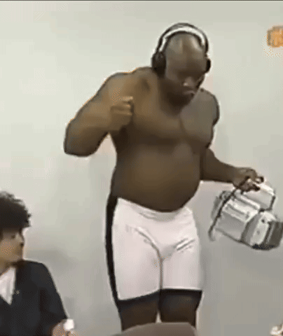 a shirtless man wearing headphones and shorts is standing in front of a camera .