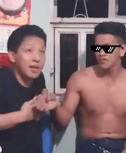 A Shirtless Man Wearing Sunglasses Talks To Another Man GIF