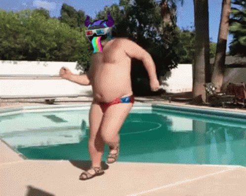 A Shirtless Man With A 3D Helmet On His Head Is Dancing By A Pool GIF