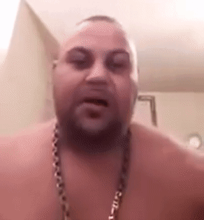 A Shirtless Man With A Beard And A Chain Around His Neck Is Talking To The Camera . GIF