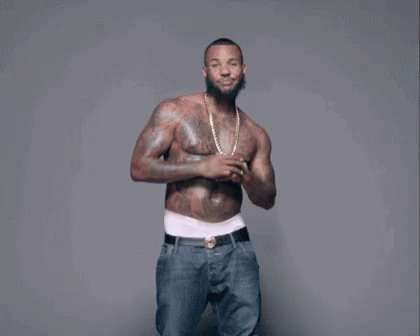 A Shirtless Man With A Beard And Tattoos Is Dancing . GIF