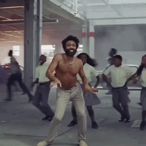 A Shirtless Man With A Beard Is Dancing In A Group Of People GIF