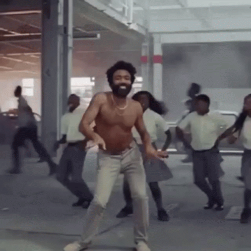 A Shirtless Man With A Beard Is Dancing With A Group Of People . GIF