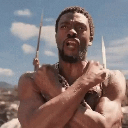A Shirtless Man With A Beard Is Holding A Spear In His Hand And Making A Funny Face . GIF