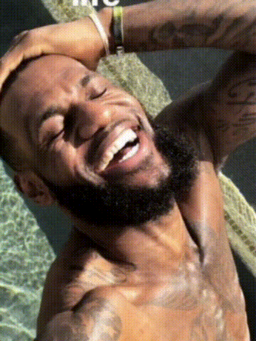 A Shirtless Man With A Beard Is Laughing With His Eyes Closed And His Hand On His Head . GIF