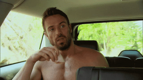 A Shirtless Man With A Beard Is Sitting In The Back Seat Of A Car GIF