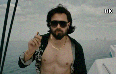 A Shirtless Man With A Beard Is Smoking A Cigarette On A Boat GIF