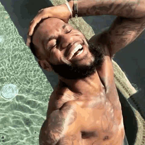 A Shirtless Man With A Beard Is Standing In A Swimming Pool . GIF