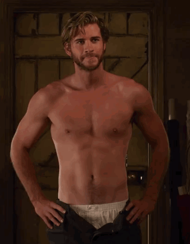 A Shirtless Man With A Beard Is Standing With His Hands On His Hips . GIF