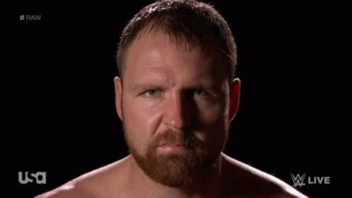 A Shirtless Man With A Beard Looks At The Camera With A Usa Logo In The Background GIF