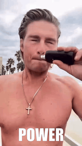 A Shirtless Man With A Cross Necklace Is Holding A Bottle In His Hand With The Word Power Written On It GIF