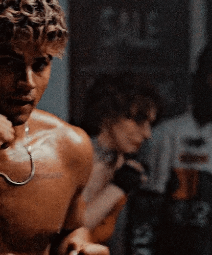 A Shirtless Man With A Hook Around His Neck Is Standing In Front Of A Mirror GIF