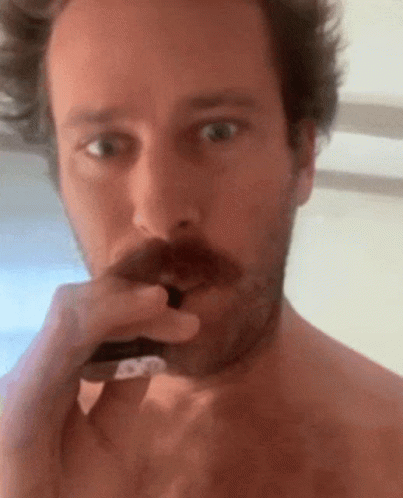 A Shirtless Man With A Mustache Is Brushing His Teeth With A Toothbrush GIF