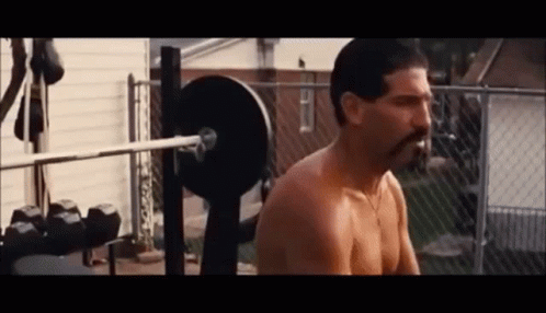 A Shirtless Man With A Mustache Is Squatting On A Bench With A Barbell . GIF