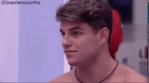 a shirtless man with a necklace around his neck is looking at something .