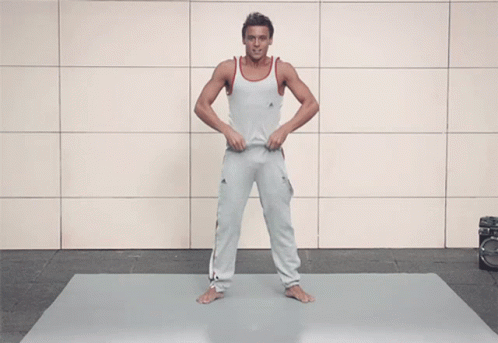 A Shirtless Man With A Tattoo On His Arm Stands On A Mat GIF