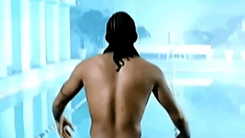 A Shirtless Man With A Tattoo On His Back Is Standing In Front Of A Swimming Pool GIF