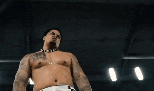 A Shirtless Man With A Tattoo On His Chest Holds His Hand Out GIF