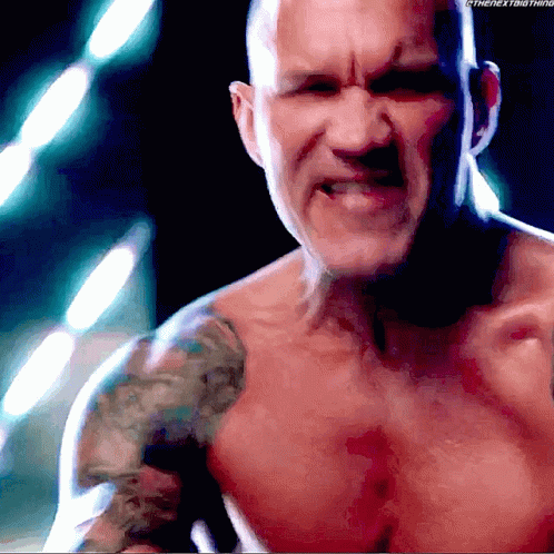 A Shirtless Man With A Tattoo On His Shoulder Is Looking At The Camera GIF