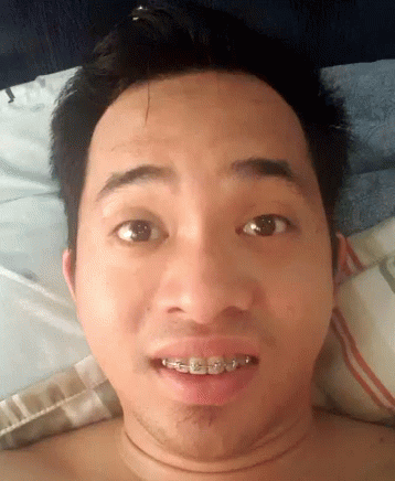 A Shirtless Man With Braces On His Teeth Is Laying On A Bed GIF