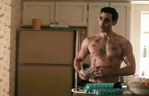 A Shirtless Man With Glasses Is Standing In Front Of A Refrigerator GIF