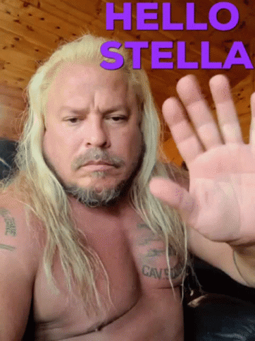A Shirtless Man With Long Blonde Hair And A Beard Waves His Hand In Front Of A Sign That Says Hello Stella GIF