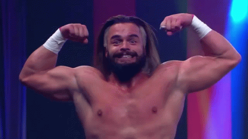 A Shirtless Man With Long Hair And A Beard Flexes His Muscles GIF