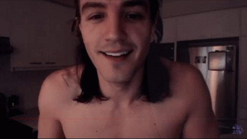 A Shirtless Man With Long Hair Smiles In A Kitchen GIF