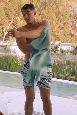 A Shirtless Man Wrapped In A Towel Stands By A Pool GIF