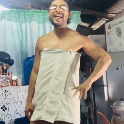 a shirtless man wrapped in a towel stands in front of a hanabishi refrigerator