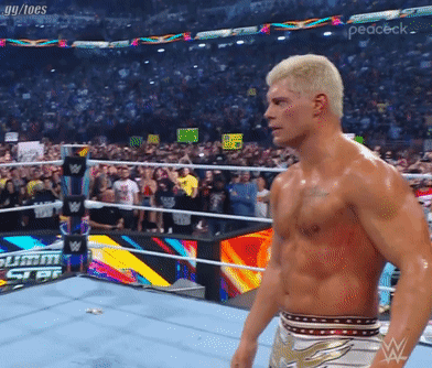 A Shirtless Wrestler In A Wrestling Ring With A Crowd Behind Him GIF
