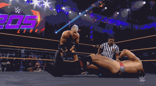 A Shirtless Wrestler In A Wrestling Ring With The Hashtag # 205Live On The Screen GIF