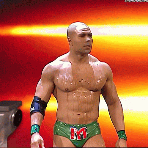 a shirtless wrestler in green underwear with the letter m on his belt