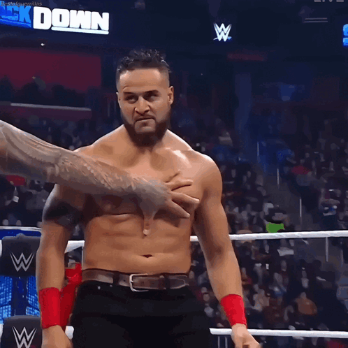 A Shirtless Wrestler Is Being Held By Another Wrestler In A Ring GIF