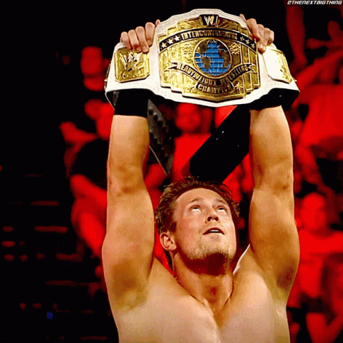 A Shirtless Wrestler Is Holding A Wrestling Championship Belt GIF