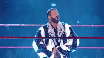 A Shirtless Wrestler Is In A Wrestling Ring With His Arms Outstretched . GIF