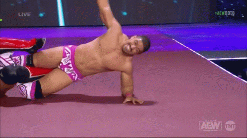a shirtless wrestler is laying on the floor during a live aew event