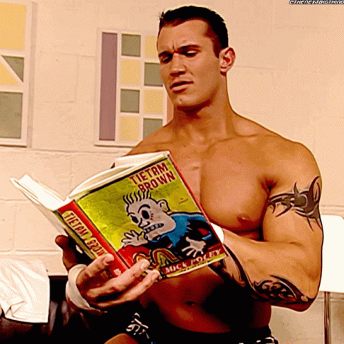 A Shirtless Wrestler Is Reading A Book Titled Tietam Brown GIF