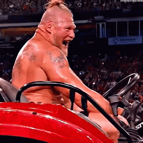 A Shirtless Wrestler Is Sitting In A Red Lawn Mower With His Mouth Open . GIF