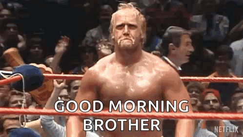 A Shirtless Wrestler Is Standing In A Wrestling Ring With A Crowd Behind Him And Says `` Good Morning Brother '' . GIF