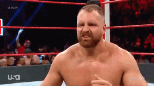 A Shirtless Wrestler Is Standing In A Wrestling Ring With A Usa Logo Behind Him GIF