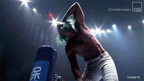 a shirtless wrestler is standing in front of a blue bag that says ' njwk13 ' on it