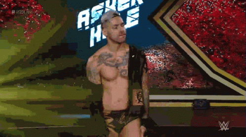 A Shirtless Wrestler Is Standing In Front Of A Sign That Says Ascension GIF