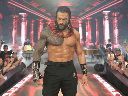 A Shirtless Wrestler Is Walking Down A Ramp With A Crowd Watching GIF